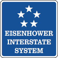 A blue square sign with five stars and the words 'Eisenhower Interstate System.'